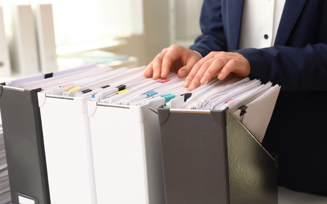 Person organizing paperwork in labeled file folders for the international adoption dossier