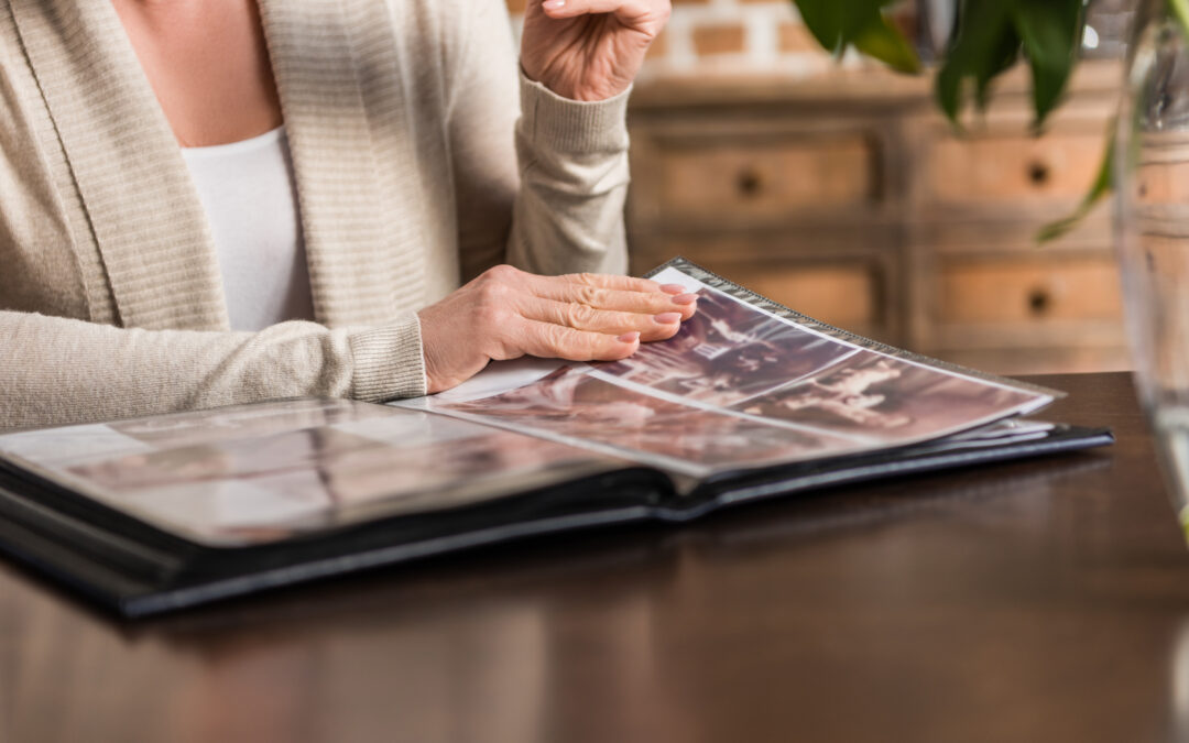 Portrait of senior gray hair woman sitting at kitchen table and looking at photo album